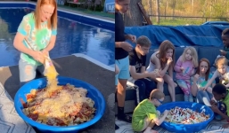 A mother serves a meal to 12 children in a baby pool