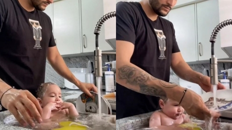 Father is criticized for putting his baby in the kitchen sink and bathing the baby while washing dishes