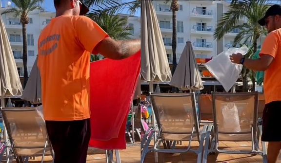 Staff remove belongings from occupied pool loungers at resort