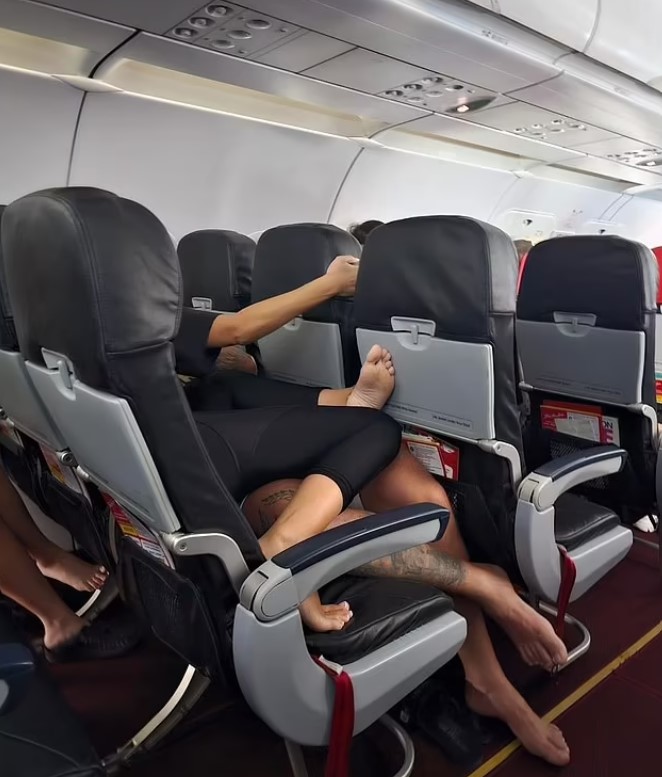 Passengers baffled as couple get intimate while lying down across a row of seats barefoot during flight 1