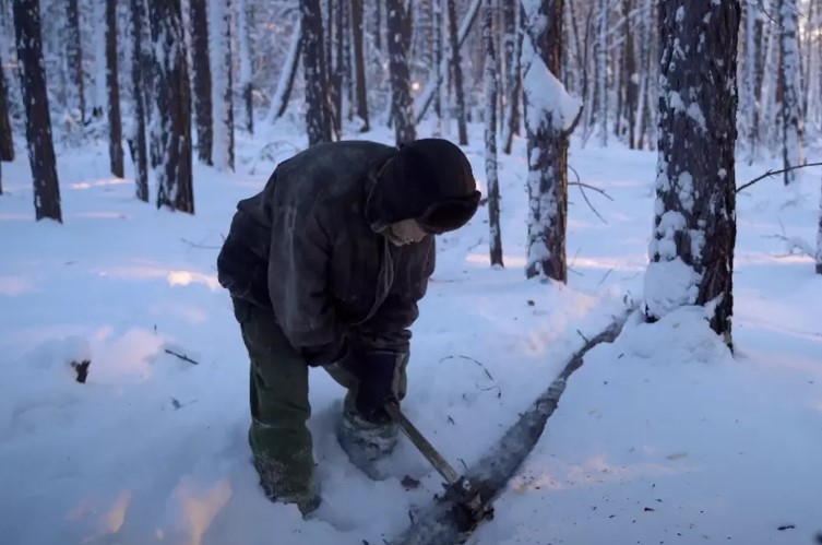 Samuil chops wood for warmth, uses makeshift cellophane 