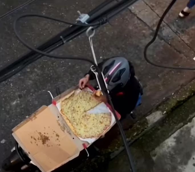 After sealing the box with sticky tape, the deliveryman continues on his way, leaving with a slightly smaller pizza than before. Image Credits: Jam Press